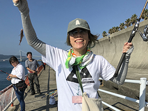 釣れた魚を持っている笑顔の女性スタッフ