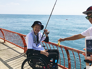 釣れた魚を持っている笑顔の車椅子男性